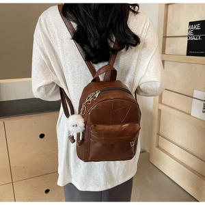 Close-up of brown PU leather backpack with geometric patchwork and cute plush charm