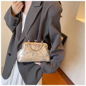 Detail of vintage evening bag with blue floral embroidery and golden metal clasp handle