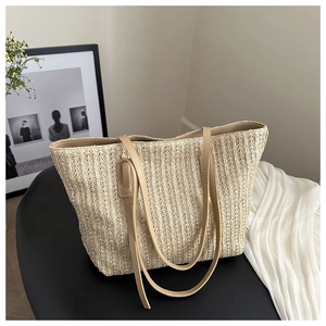 Detailed close-up of beige woven straw tote bag with brown leather shoulder straps