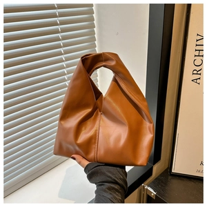 Detail showing smooth caramel brown PU leather texture and vertical stitching on the bucket bag