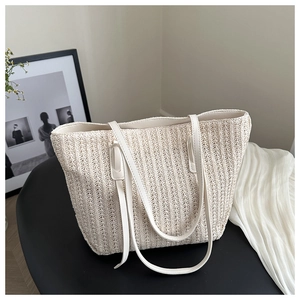 Detailed view of the vertical straw woven texture and white leather strap of the tote bag