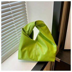 Detailed close-up of a bright green pleated leather handbag with a signature knot handle