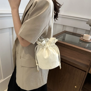 Minimalist beige drawstring bucket bag featuring a ruffled top and textured faux leather