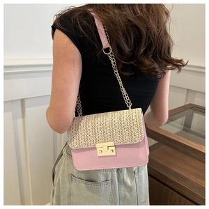Detail of a pink leather and beige straw patchwork crossbody bag with gold metal clasp