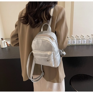 Detailed view of silver mini backpack with geometric stitching and shiny metallic finish