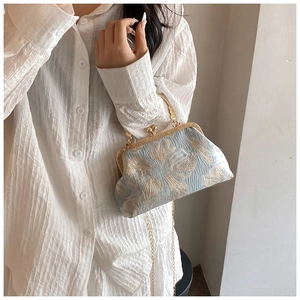 Detail of blue floral jacquard evening bag with engraved gold frame and chain strap