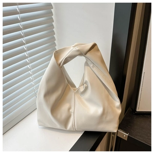 Detailed close-up of a soft beige pleated cloud bag with a unique knotted handle design