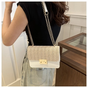 Detail of a straw texture crossbody bag with gold chain strap shown on a model