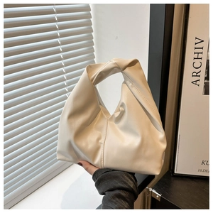 Detail view of the pleated beige leather handbag with creative knotted handle design