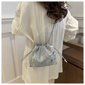 Detail of silver drawstring bucket bag with 3D butterfly charms and metal chain strap