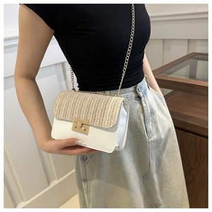 Detail shot of straw woven shoulder bag with white leather and gold chain strap