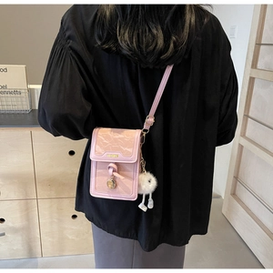 Detail of pink pleated crossbody bag with gold fashion plaque and fluffy white pompom