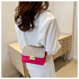 Detail view of pink and beige straw woven crossbody bag with gold chain strap on a model
