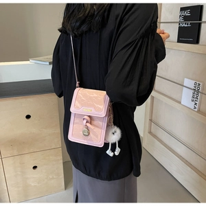 Pink embossed leather crossbody bag with knot detail and plush monster charm