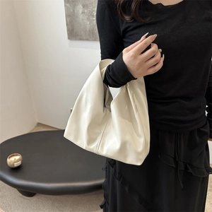 Minimalist cream white pleated bucket bag shown in a professional lifestyle setting