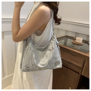 Detail of silver pleated crescent bag with metallic butterfly accents and chain strap