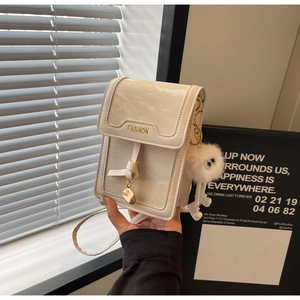 Detail of white marble textured crossbody bag with gold fashion plate and plush monster charm