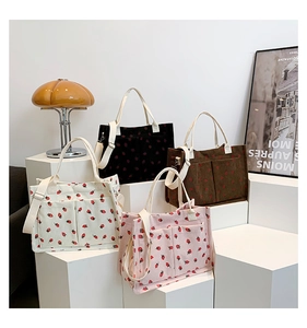 Detail view of corduroy tote bags in four colors with red strawberry patterns and straps