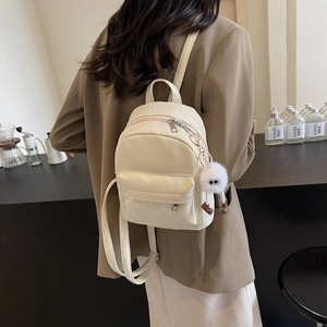 Minimalist cream white leather mini backpack with textured quilting and plush charm