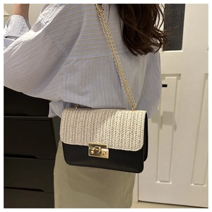 Detail of fashion crossbody bag featuring woven straw texture and gold chain strap