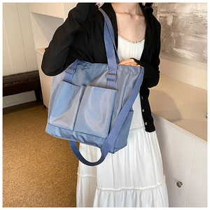 Close-up of light blue canvas tote bag with dual front pockets and adjustable shoulder strap