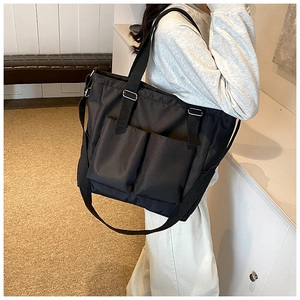 Detail view of black large capacity tote bag with dual front pockets and wide straps