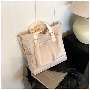 Detail view of beige canvas tote bag with front pockets and adjustable strap