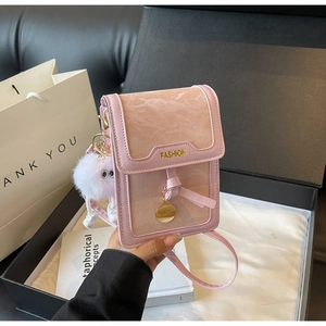 Detail of pink mini shoulder bag with marble texture, gold buckle and plush monster charm