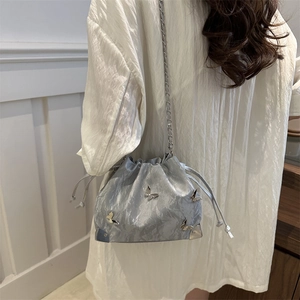 Silver drawstring bucket bag with metallic pleated texture and 3D butterfly charms