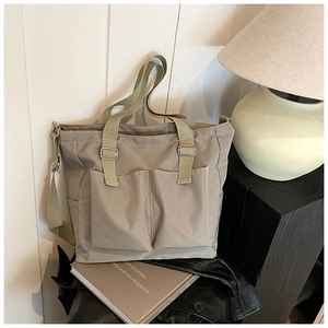 Detail view of khaki canvas tote bag with front pockets and adjustable strap for daily use