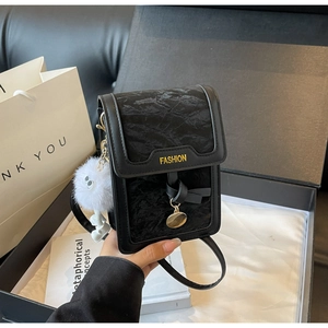 Detail of black mini crossbody bag with wrinkled texture and plush pompom in a gift box