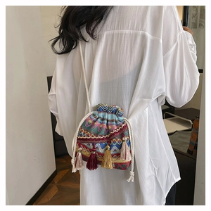 Détail du sac seau tissé coloré avec des glands multicolores et une bandoulière en coton