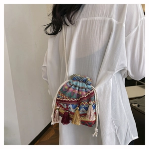 Détail d'un sac seau tissé bohème aux motifs colorés avec des franges décoratives