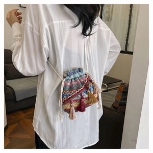 Détail d'un sac seau tissé avec motifs arc-en-ciel et glands sur une chemise blanche