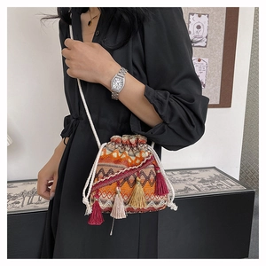 Détail du sac seau bohème tissé avec motifs géométriques et longues franges à pompons