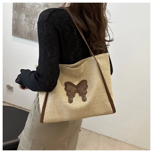 Detail of hand-woven tote bag with brown leather butterfly applique and slim shoulder straps
