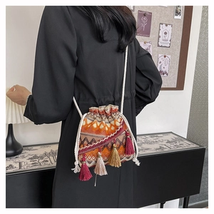 Détail d'un sac seau tissé avec motifs géométriques et pampilles à franges colorées