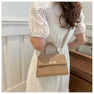 Détail de la texture crocodile kaki et du fermoir rotatif doré sur le sac à main chic
