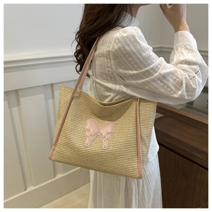 Detail of summer straw tote bag with pink leather butterfly and woven texture