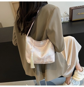 Detail der rosa Seiden-Tasche mit floralem Jacquard-Muster und langem weißen Quasten-Anhänger