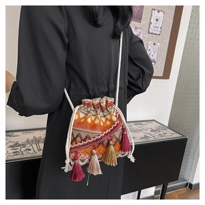 Détail d'un sac seau tissé avec des motifs ondulés colorés et des franges denses