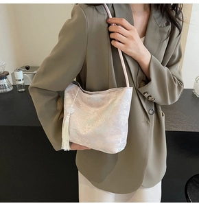 Detail der floralen Jacquard-Stofftasche in Perlweiß mit langer Seidenquaste-Verzierung
