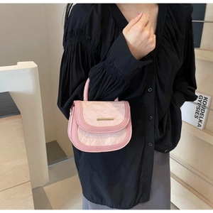 Detailed view of a pink mini saddle bag with stone texture flap and gold buckle