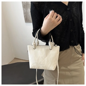 Détail du sac seau texturé marbre blanc avec poignée nouée et lettrage doré élégant