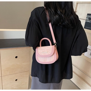 Detail of pink saddle bag featuring pleated texture and gold bar on adjustable strap