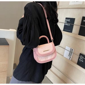 Detail of pink saddle bag with marble texture flap and golden hardware accents