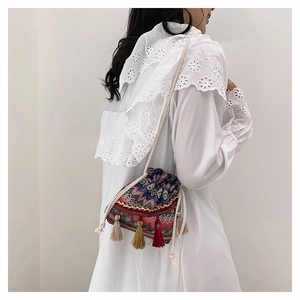 Détail du sac seau tissé bohème avec motifs géométriques multicolores et franges