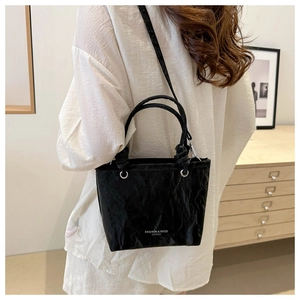 Détail du sac cabas en cuir plissé noir avec lettrage blanc et doubles poignées rondes