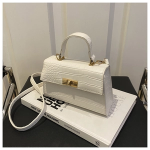 Gros plan d'un sac à main blanc motif crocodile avec fermoir rotatif doré chic