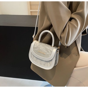 Detail showing marble texture flap and gold metal bar on silver crossbody saddle bag